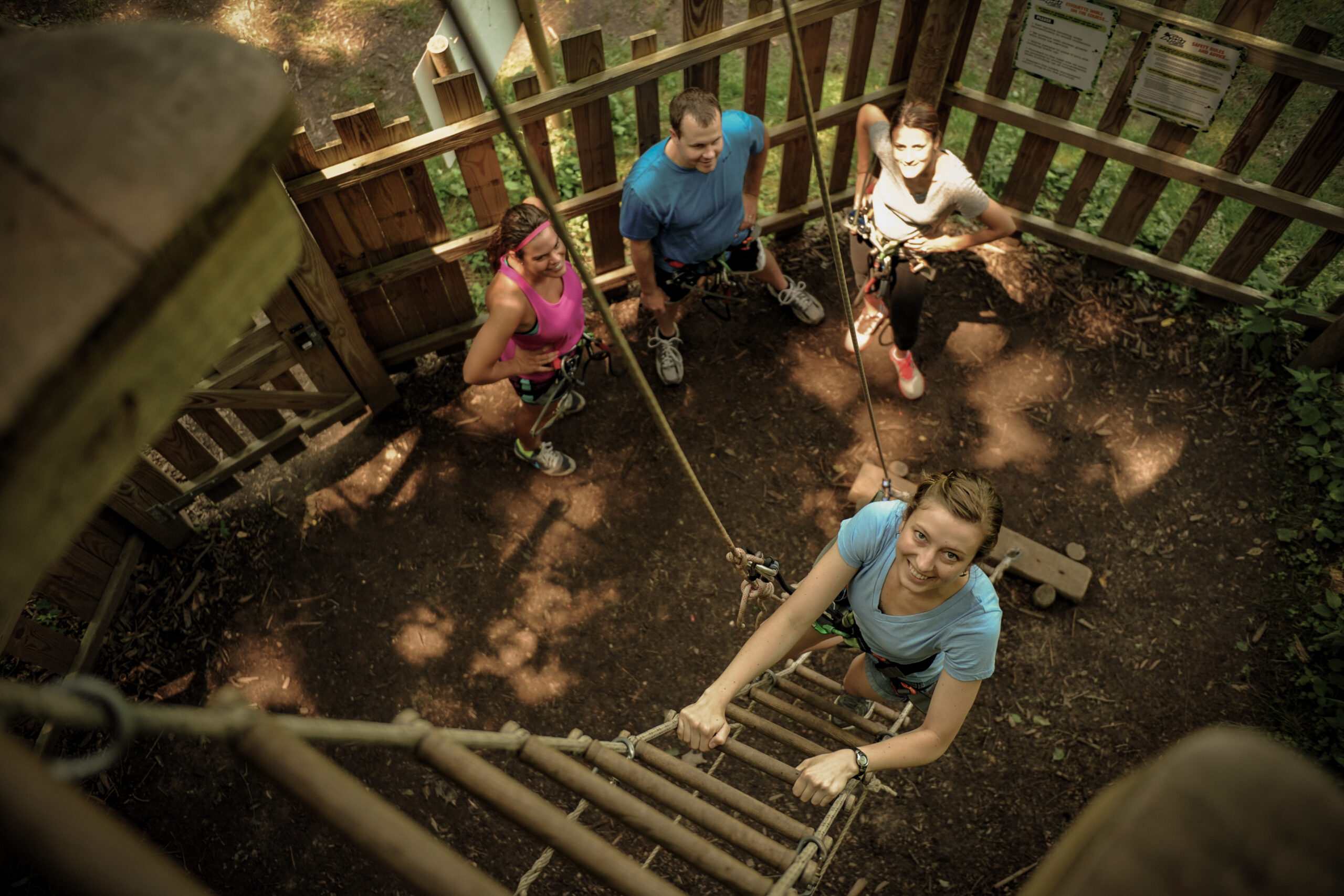 Woman climbing a ladder with supportive teammates