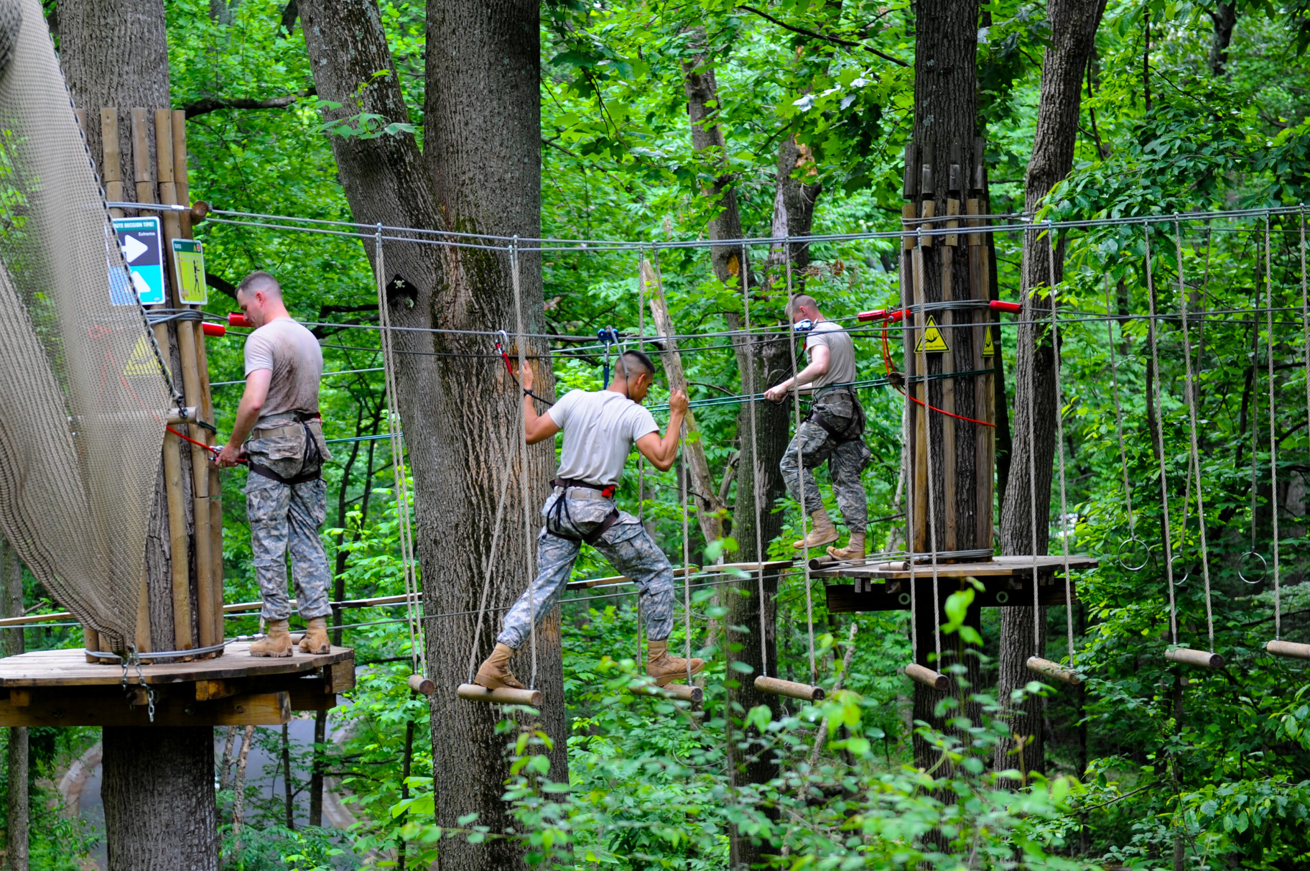 Young army members completing an aerial adventure course as a team