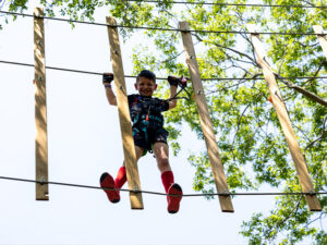 A young boy conquering a treetop bridge in Arlington, Texas
