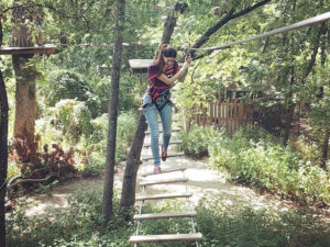 Young woman crosses a treetop rope bridge in Plano, Texas