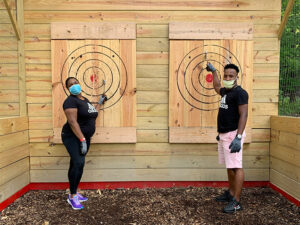 Two people posing triumphantly next to axe throwing targets in Cleveland, Ohio