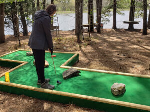 A young woman taking a swing at a minigolf course through the forest in Memphis, Tennessee