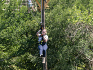 A young woman flying down a zipline through the forest in Arlington, Texas