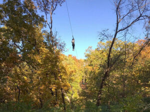 A person flying down a zipline through a beautiful forest canopy in Kansas City, Missouri